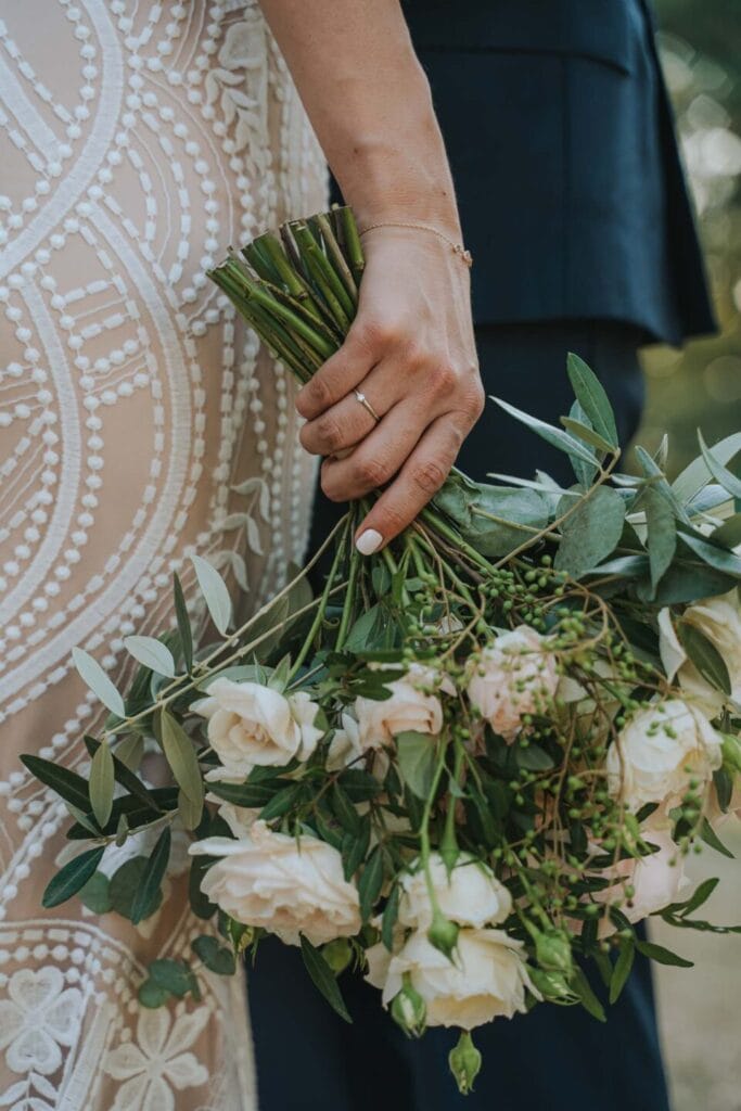 dettaglio del bouquet di una sposa fatto di rose bianche preso da vicino al suo fianco durante servizio fotografico di matrimonio di yelley photography