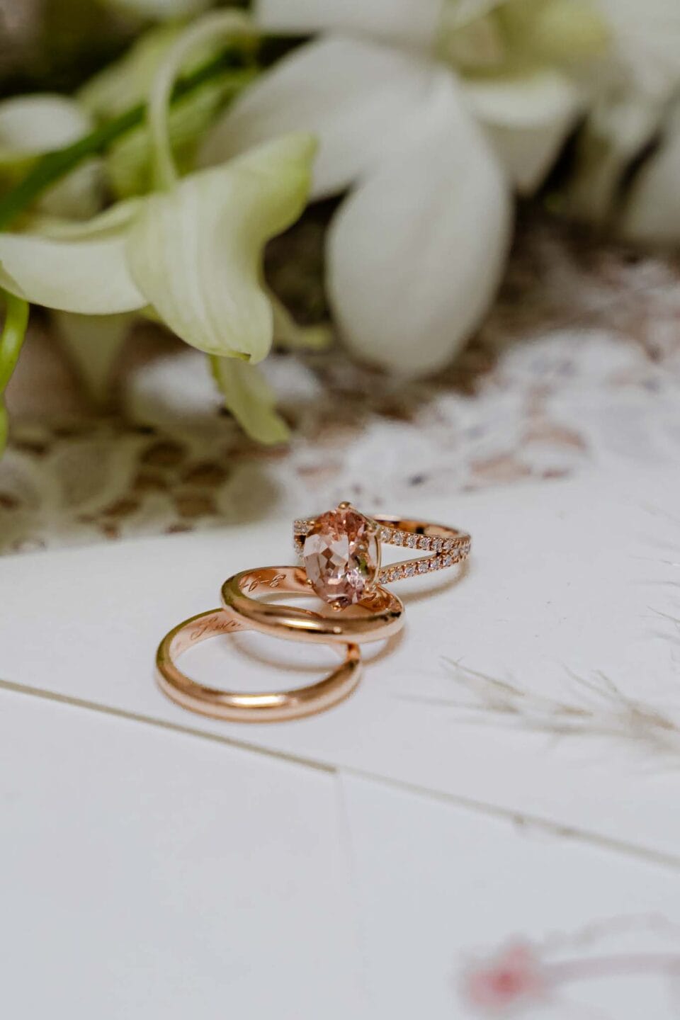 Dettaglio anelli degli sposi, fedi nuziali, sistemate una sopra l'altra accanto al bouquet e alla partecipazione di matrimonio durante i preparativi degli sposi nel servizio fotografico di yelley photography, anello di fidanzamento di morganite
