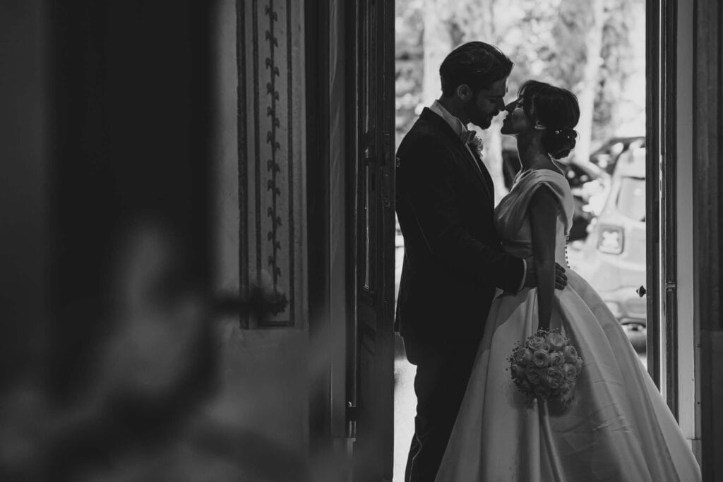 foto in bianco e nero della silhouette di due sposi uno davanti all'altro con alle spalle una porta che da sul cortile di villa cimena in piemonte, durante servizio fotografico di yelley photography