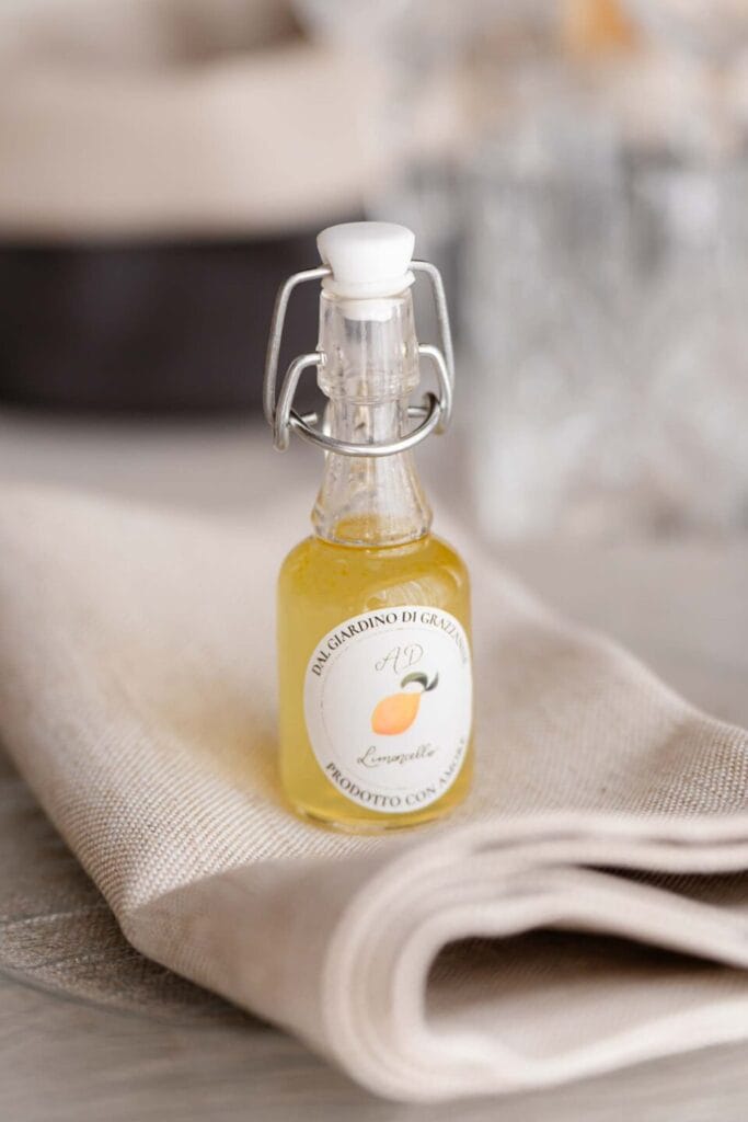 Bomboniera gastronima bottiglietta di limoncello sul tavolo del ricevimento di matirmonio, poggiata sopra al tovagliolo piegato per una idea originale