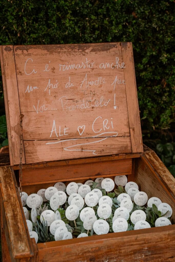 Foto di una scatola di legno aperta contenente delle piantine con un cartellino di ringraziamento che fungono da bomboniere di matrimonio originali